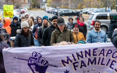 A large group of community members marches behind a banner supporting Minneapolis Families for Public Schools.