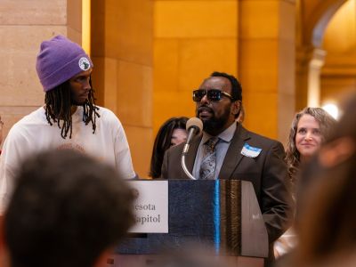 A community member speaking at a podium in the Minnesota State Capital in support of Public schools.