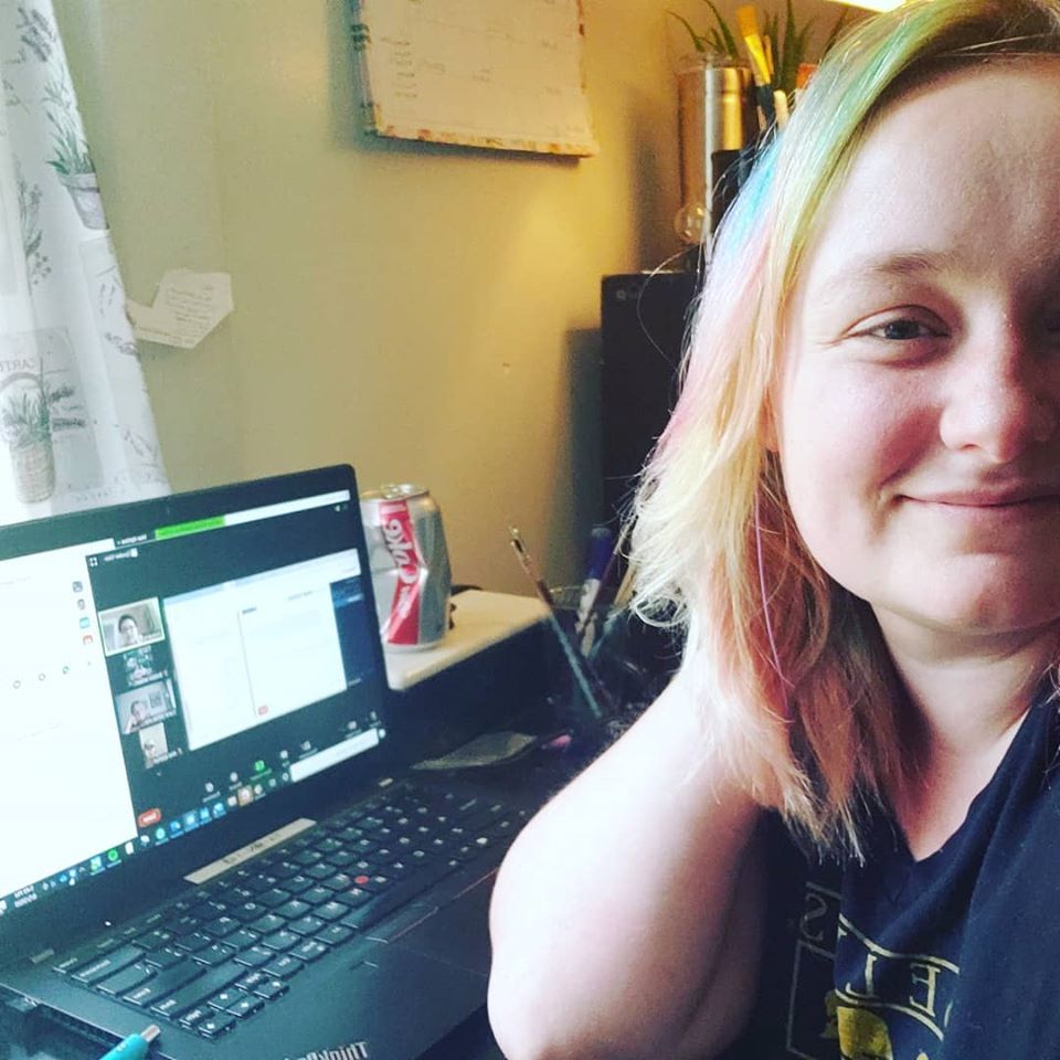 A photo of blog contributor Britton Mikkelson during the 2020 election season. Britton is sated at her desk, facing the camera, with a phonebank screen visible on the laptop next to her. 