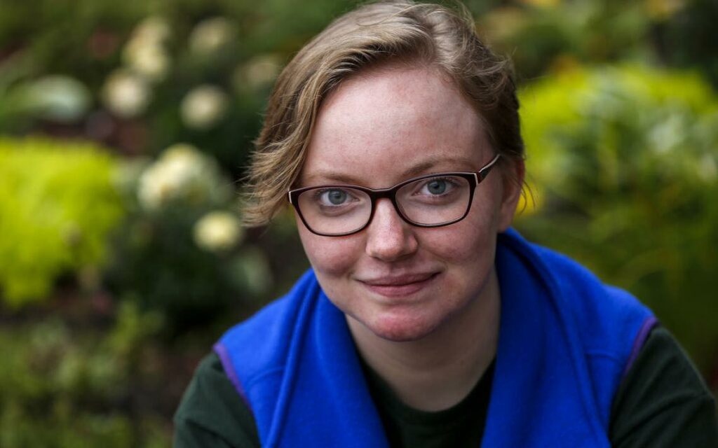 Helen Clanaugh of Duluth wears a blue vest and faces the camera. The photo is set outdoors, with greenery in the background.