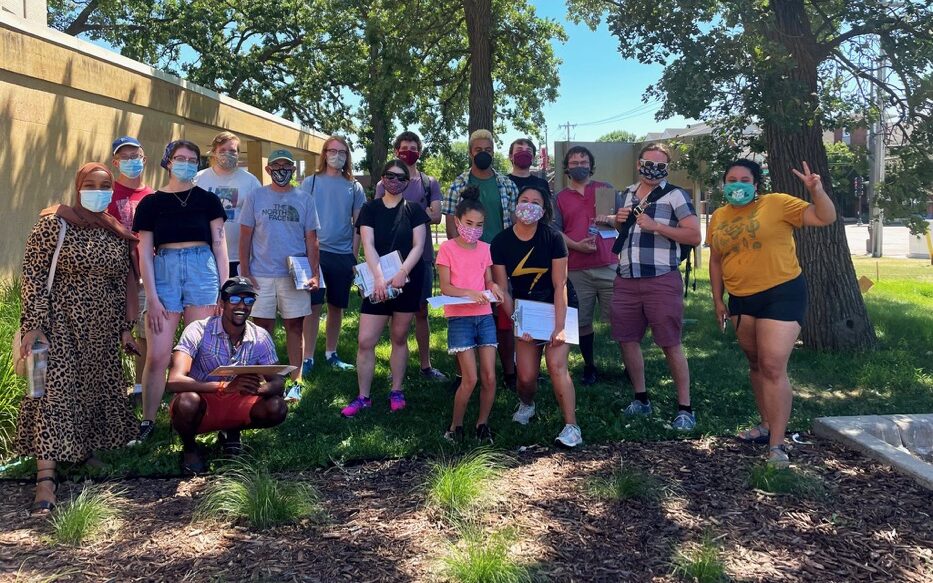 Volunteers with St. Paul City Council Member Mitra Jalali take a photo with clipboards while doorknocking for signatures