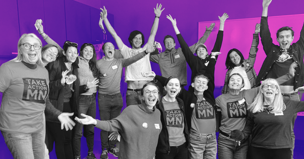 A group of people wearing TakeAction Minnesota tshirts smiling, in a celebratory pose